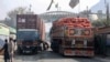 Truk yang membawa barang melewati titik nol perbatasan Torkham antara Afghanistan dan Pakistan, di provinsi Nangarhar, setelah pintu penyeberangan perdagangan utama tersebut dibuka kembali 23 Januari 2024. (Syafiullah KAKAR/AFP)