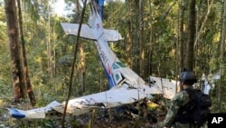 Dalam foto yang dirilis Kantor Pers Angkatan Bersenjata Kolombia tampak seorang tentara Kolombia di depan rongsokan pesawat Cessna C206 yang jatuh di hutan Solano, negara bagian Caqueta, Kolombia, Kamis, 18 Mei 2023. (Foto: Colombia's Armed Forces Press Office via AP)