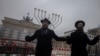 Dua rabi menari di depan Hanukkah Menorah raksasa, yang didirikan oleh Pusat Pendidikan Yahudi Chabad di depan Gerbang Brandenburg di pusat kota Berlin, Jerman. 