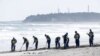 Polisi mencari petunjuk tentang orang hilang dari bencana gempa bumi dan tsunami tahun 2011 di pantai dekat PLTN Fukushima Daiichi yang lumpuh akibat tsunami di kota Namie, prefektur Fukushima, Jepang, 11 Maret 2024, pada peringatan 13 tahun bencana tersebut. (Kyodo via REUTERS)
