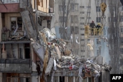 Tim penyelamat membersihkan puing-puing dari gedung bertingkat yang rusak berat akibat serangan pesawat tak berawak, di Odesa pada 3 Maret 2024, di tengah invasi Rusia ke Ukraina. (Foto: AFP)
