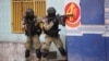 Yon polisye pran pozisyon pou pwoteje tet li pandan yon operasyon anti-gang nan katye Potay la nan Potoprens, 29 Fevriye, 2024. 