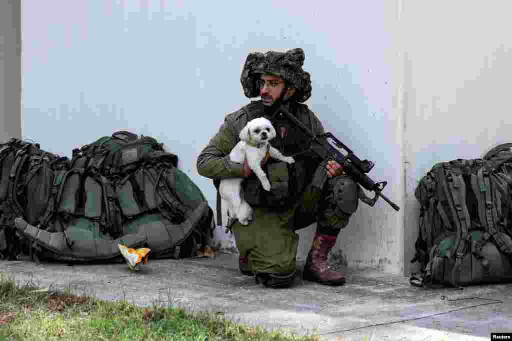 An Israeli soldier holds a rescued dog as he takes position near a bomb shelter in Kibbutz Kfar Aza, in southern Israel. REUTERS/Ronen Zvulun 