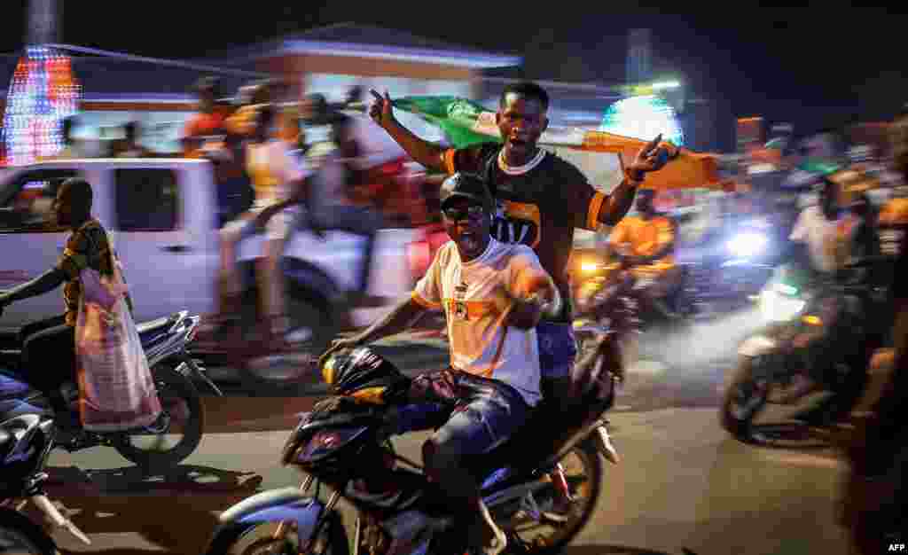 Des supporters ivoiriens défilent dans la rue à Korhogo, dans le nord de la Côte d'Ivoire, le 13 janvier 2024, après que l'équipe de football de Côte d'Ivoire a remporté le match de football entre la Côte d'Ivoire et la Guinée-Bissau lors de la Coupe d'Afrique des Nations (CAN) de 2024.