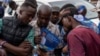 Des supporteurs de l'"Union sacrée de la nation", une coalition politique autour du président Tshisekedi, scrutent les résultats des élections sur un téléphone portable.