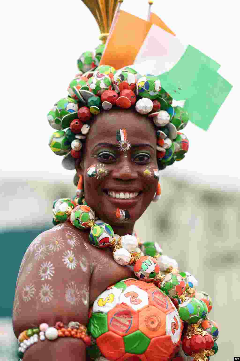 Une supportrice avec des drapeaux de la Côte d'Ivoire peints sur son visage réagit avant la cérémonie d'ouverture de la Coupe d'Afrique des Nations (CAN) 2024 au stade olympique Alassane Ouattara à Ebimpe, Abidjan, le 13 janvier 2024.