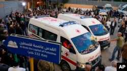 Jounalis ak manm fanmi yo rasanble bo kote anbulans La Kwa Wouj Libanez kap transpote kadav 2 jounalis rezo televizyon Arab Al-Mayadeenm TV nan Beirout, Liban 21 Nov. 2023.