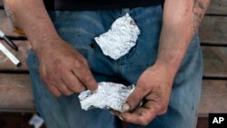 Seorang pria bersiap untuk merokok fentanil di sebuah bangku taman di Portland, Oregon, pada 18 Mei 2023. (Foto: Beth Nakamura/The Oregonian via AP)