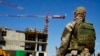 Seorang tentara Rusia menjaga lokasi gedung apartemen baru yang sedang dibangun dengan dukungan Kementerian Pertahanan Rusia, di Mariupol, di wilayah di bawah kendali Pemerintah Republik Rakyat Donetsk. (Foto: AP)