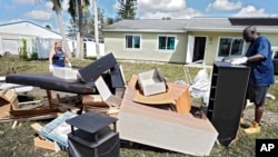 Andre McCourt, a la derecha, y su esposa Sandra sacan muebles anegados de su casa, el 4 de octubre de 2022, en North Port, Florida, EE.UU.