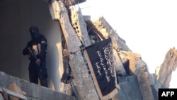 Seorang anggota pasukan kelompok teroris jaringan al-Qaeda, Front Al-Nusra, beridir di dekat bangunan gedung yang hancur di kamp pengungsi Palestina Yarmuk di Damaskus, Suriah, pada 22 September 2014. (Foto: AFP/Rami Al-Sayed)