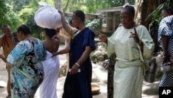 Devotees of the Osun River goddess prepare to perform sacrifices for a woman draped in a white cloth in Osogbo, Nigeria, on May 29, 2022.