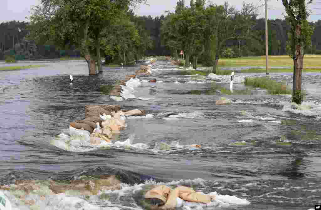 Karung-karung pasir yang digunakan untuk membendung air terhempas banjir di sebuah jalan antara Wulkau dan Kamern, Jerman. Air di Sungai Elbe, Sungai Danube, dan sungai lainnya meluap karena derasnya hujan, mengakibatkan kerusakan yang parah selama dua minggu ini di Jerman selatan dan timur laut.