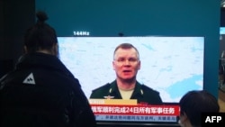 Residents watch a TV screen showing news about conflict between Russia and Ukraine at a shopping mall in Hangzhou, in China' on Feb. 25, 2022. 
