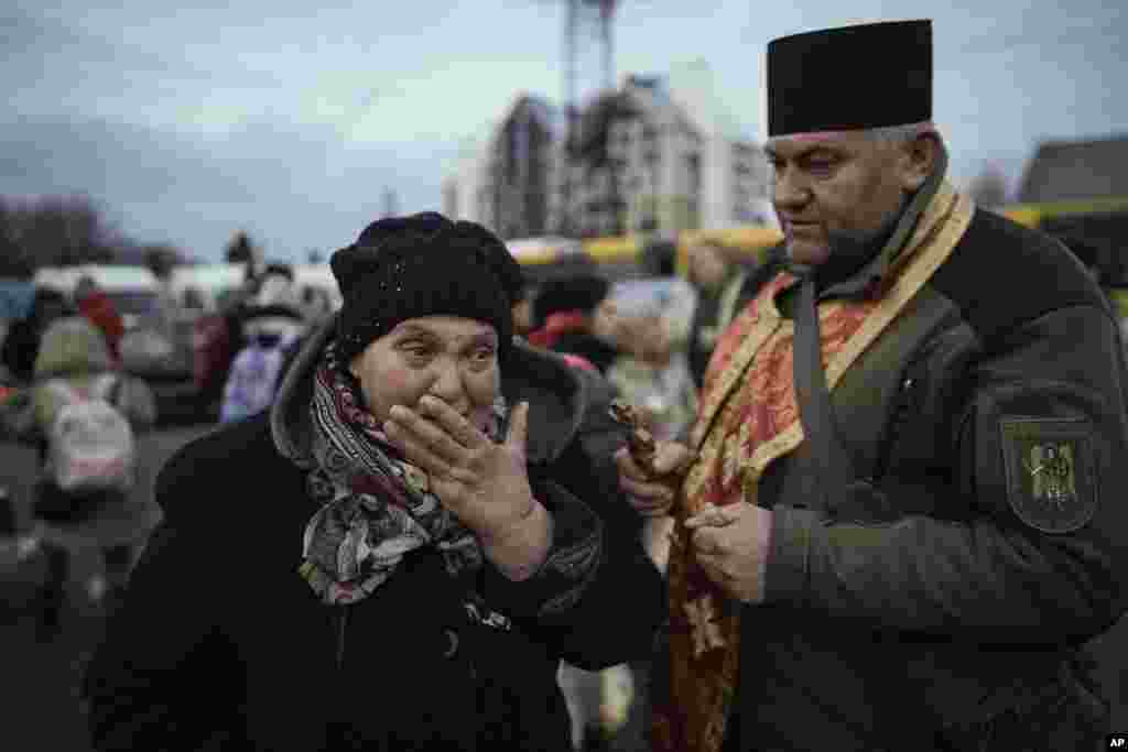 A military priest comforts a woman who was evacuated from Irpin, at a triage point in Kyiv, March 9, 2022. A Russian airstrike devastated a maternity hospital in the besieged port city of Mariupol amid growing warnings from the West that Moscow's invasion is about to take a more brutal and indiscriminate turn.