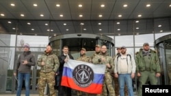 Sejumlah pengunjung berpose di luar kantor PMC Wagner Centre, sebuah proyek yang dijalankan oleh pendiri grup militer swasta Wagner, Yevgeny Prigozhin, dalam kunjungan mereka ke kantor tersebut di Saint Petersburg, Rusia, pada 4 November 2022. (Foto: Reuters/Igor Russak)