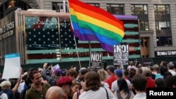 FILE - A rainbow flag flies as people protest U.S. President Donald Trump's announcement that he plans to reinstate a ban on transgender individuals from serving in any capacity in the U.S. military, in Times Square, in New York City, July 26, 2017. 