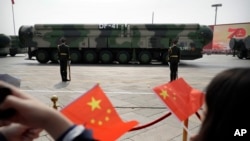 ARCHIVO - Espectadores ondean banderas chinas mientras vehículos militares con misiles balísticos DF-41 ruedan durante un desfile para conmemorar el 70 aniversario de la fundación de la China comunista en Beijing, el 1 de octubre de 2019.
