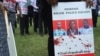 FILE - A protester holds a sign picturing human rights attorney, Willie Kimani; his client, Josephat Mwenda; and their taxi driver, Joseph Muiruri, allegedly killed by police, at a rally in Nairobi, Kenya, July 4, 2016. (J. Craig/VOA)