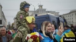 Penduduk setempat berfoto dengan prajurit Ukraina setelah mundurnya Rusia dari kota Kherson, di pusat kota Kherson, Ukraina, 12 November 2022. (Foto: Reuters)