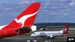 FILE - Two Qantas passenger jets sit on the tarmac and runway at Sydney International Airport, in Sydney, Australia, July 27, 2000.