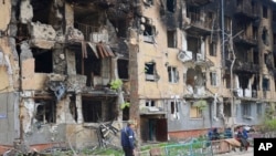 Seorang pria tampak berjalan melewati gedung apartemen yang hancur di Mariupol, Ukraina, pada 4 Mei 2022. (Foto: AP/Alexei Alexandrov)
