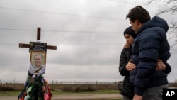 ARCHIVO - Yura Nechyporenko, de 14 años, abraza a su tío Andriy Nechyporenko sobre la tumba de su padre Ruslan Nechyporenko en el cementerio de Bucha, en las afueras de Kiev, Ucrania, el 21 de abril de 2022.