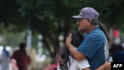 Families hug outside the Willie de Leon Civic Center where grief counseling will be offered in Uvalde, Texas, on May 24, 2022. (Photo AFP/Allison Dîner)