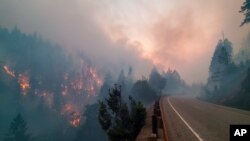 In this photo provided by the Oregon Department of Transportation flames from the Jack Fire burn along Oregon 138 near Steamboat, about 40 miles east of Roseburg, Oregon, July 7, 2021.