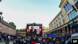 FILE - Spectators attend the award ceremony at the 71st Berlinale Summer Festival at the open-air cinema Museum Island. A photo of Mohammad Rasoulof of Iran, a member of the 2021 International Jury, can be seen on the big screen in Berlin, Germany.