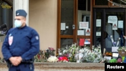 Flowers are stacked outside the school where slain history teacher Samuel Paty was working, in Conflans-Sainte-Honorine, northwest of Paris, France, Oct. 17, 2020.