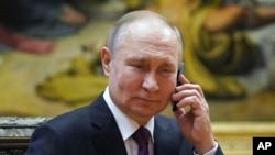 Russian President Vladimir Putin talks on the phone to eight-year-old Alexandra Titarenko from Zaporizhzhia region, a participant in the Fir Tree of Wishes charity campaign at the State Russian Museum in St. Petersburg, Russia, Tuesday, Dec. 27, 2022. 