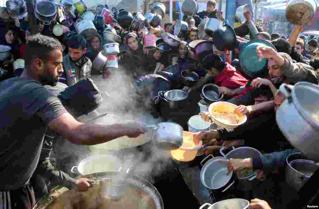 Palestinians gather to receive food cooked by a charity kitchen in Khan Younis in the southern Gaza Strip as the Israel-Hamas conflict continues.