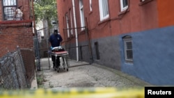 A NYC coroner carries an empty gurney at the scene of an alleged homicide in the Brooklyn borough of New York, U.S., Sept. 7, 2020.