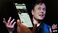 Dans cette photo d'illustration, un écran de téléphone affiche le compte Twitter d'Elon Musk avec une photo de lui en arrière-plan, le 14 avril 2022, à Washington, DC.