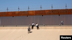 Para migran pencari suaka berjalan keluar dari sungai Rio Bravo di El Paso, Texas, seperti terlihat dari Ciudad Juarez, Meksiko, pada 13 April 2022. Para migran tersebut menemui para petugas patroli perbatasan AS untuk mengajukan suaka. (Foto: Reuters/Jose Luiz Gonzalez) 