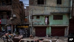 Seorang pria Muslim mengawasi dari rumahnya di lingkungan Jahangirpuri barat laut New Delhi, India, Rabu, 20 April 2022, setelah sebuah toko di daerah tersebut dihancurkan dalam kekerasan komunal pada hari Sabtu lalu. (AP Photo/Altaf Qadri)