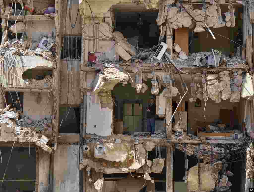 A man watches rescuers sift through the rubble as they search for people still missing at the site of Friday's Israeli strike in Beirut's southern suburbs, Lebanon.