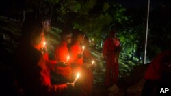FILE - Faithful hold candles below the Heroes of the Battle of Vertieres monument during a voodoo ceremony one day before the 214th anniversary of the battle that led to Haiti's independence from France in Cap Haitien, Haiti, Nov. 17, 2017.
