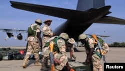 Des soldats nigérians se préparent à charger des caisses dans un avion militaire à l'aéroport de Kaduna, dans l'État de Kaduna, au nord du Nigeria, le 17 janvier 2013.
