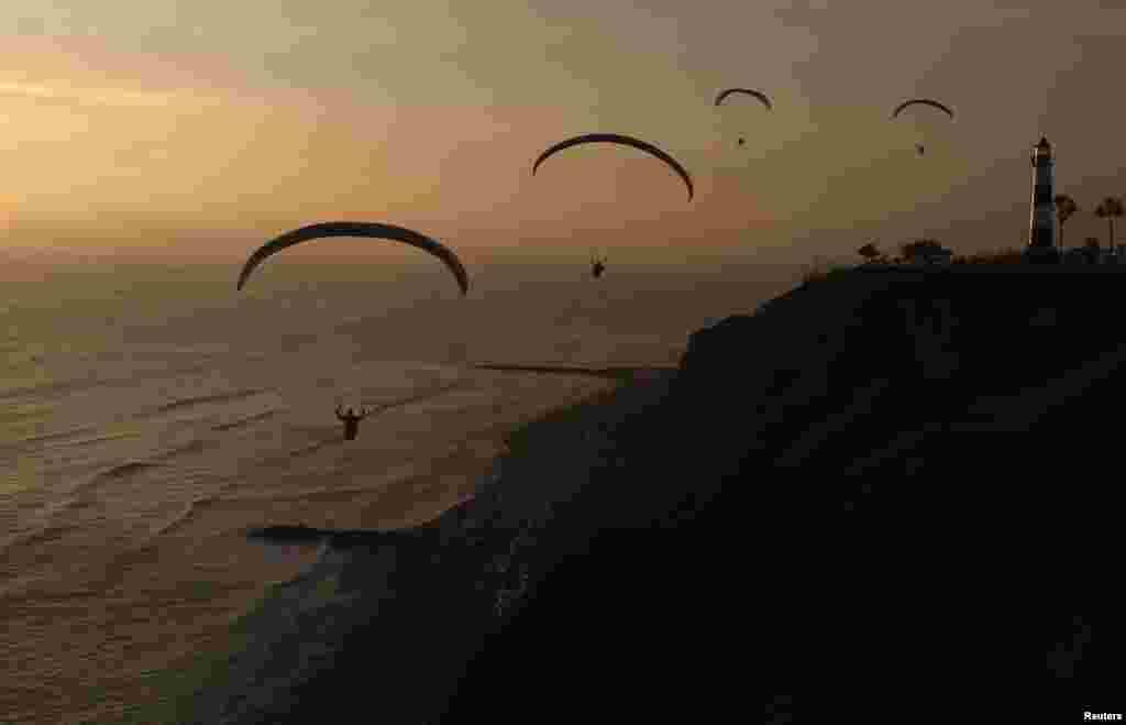 Para penerjun payung (paraglider) tampak terbang di perbukitan distrik Miraflores, kota Lima, Peru.