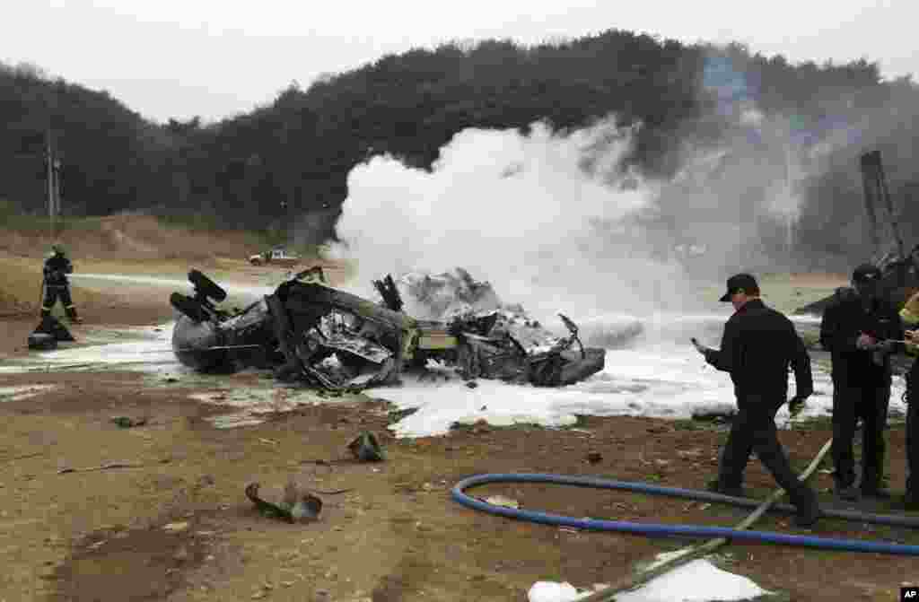 A firefighter tries to extinguish a U.S. Marine helicopter after it made a "hard landing" during an exercise, north of Seoul, April 16, 2013.