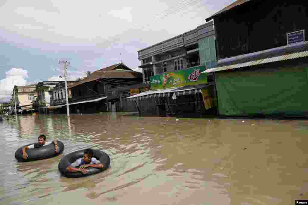 Orang-orang mengarungi jalanan yang banjir di Kalay, kawasan Sagaing, 2 Agustus 2015.