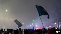 FILE - Protesters wave flags during thousands-strong march in Almaty, Kazakhstan's largest city, after protests that began over fuel prices threatened to spiral out of control, Jan. 4, 2022.