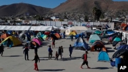 Sekelompok kaum migran berjalan di tempat yang dahulunya menjadi lokasi konser dan sekarang berfungsi sebagai lokasi penampungan di Tijuana, Meksiko, Senin, 3 Desember 2018 (foto: AP Photo/Rebecca Blackwell)