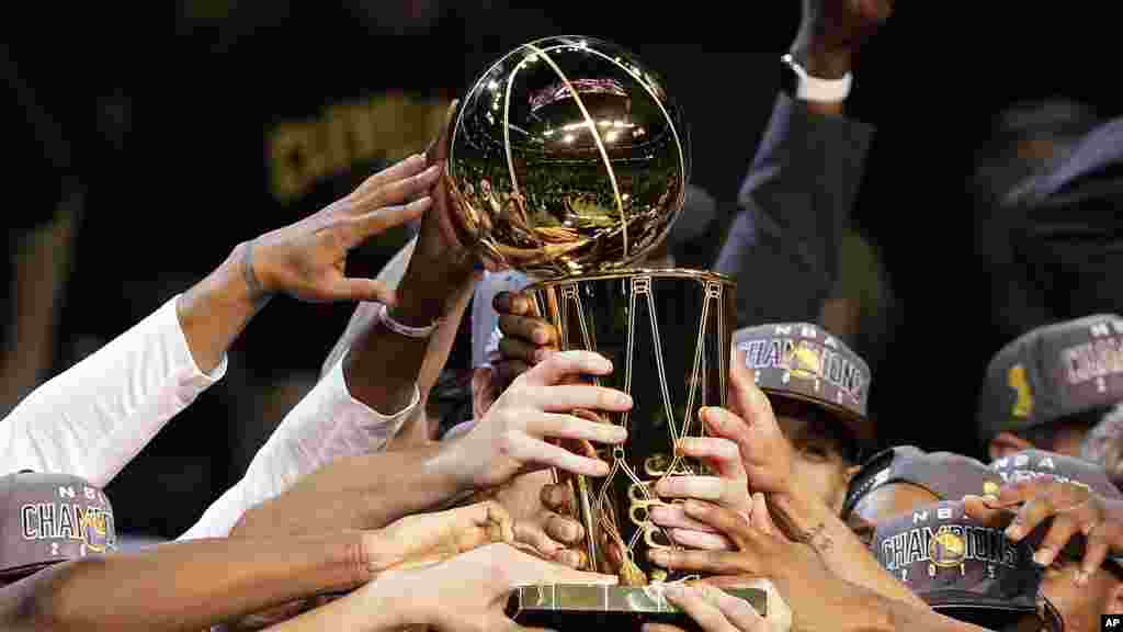 'Yan kungiyar Golden State, rike da kofin da suka lashe suna nuna murnarsu, ranar Laraba 17, ga watan Yuni. 2015.