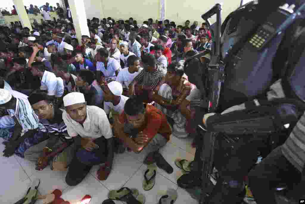Polisi berjaga-jaga saat para pria etnis Rohingya yang baru tiba berkumpul di tempat penampungan sementara di Lhoksukon, Aceh (13/5). (AP/Binsar Bakkara)
