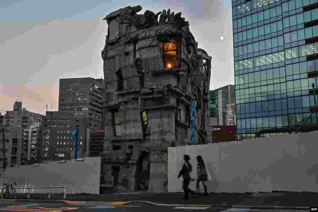 This photo taken on Nov. 13, 2024 shows pedestrians walking past the four-storey Arimaston Building by Japanese architect Keisuke Oka in the Mita area of Minato Ward in Tokyo. Passers-by stop and stare at the ramshackle, hand-built concrete tower that looks like it has been lifted right out of a Japanese animation and dropped onto a real-life Tokyo street. Oka started construction in 2005. Apart from the help of a few friends, he made the entire building himself by hand. 