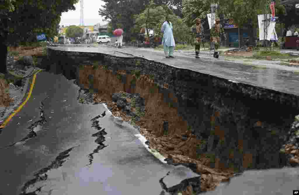 میرپور کے علاقے جاتلان میں پاکستان آرمی کے اہلکار ایک تباہ شدہ سڑک کے قریب سے گزر رہے ہیں۔ 