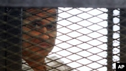 Al Jazeera journalist Peter Greste looks out from the defendant's cage during a sentencing hearing in a courtroom in Cairo, Egypt, June 23, 2014.